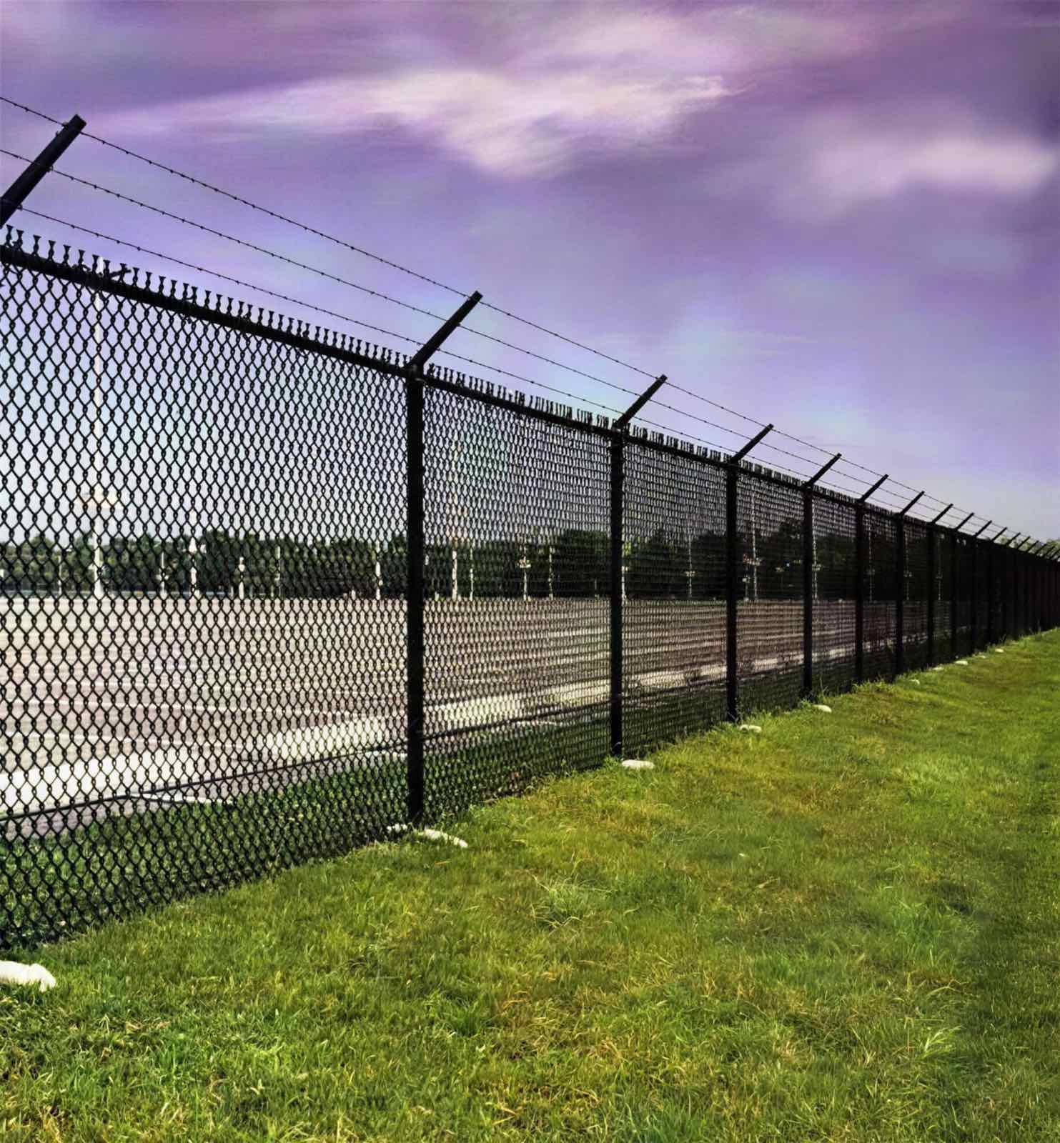 Black vinyl-coated chain link fence around a commercial lot
