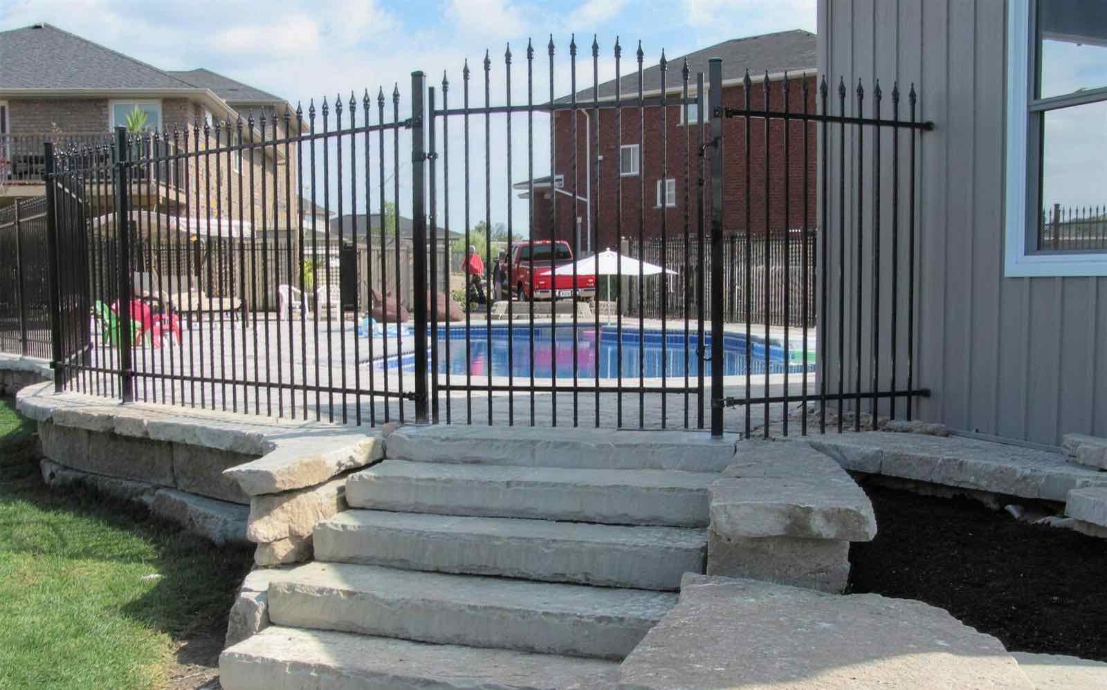 Black ornamental iron fence around a backyard pool