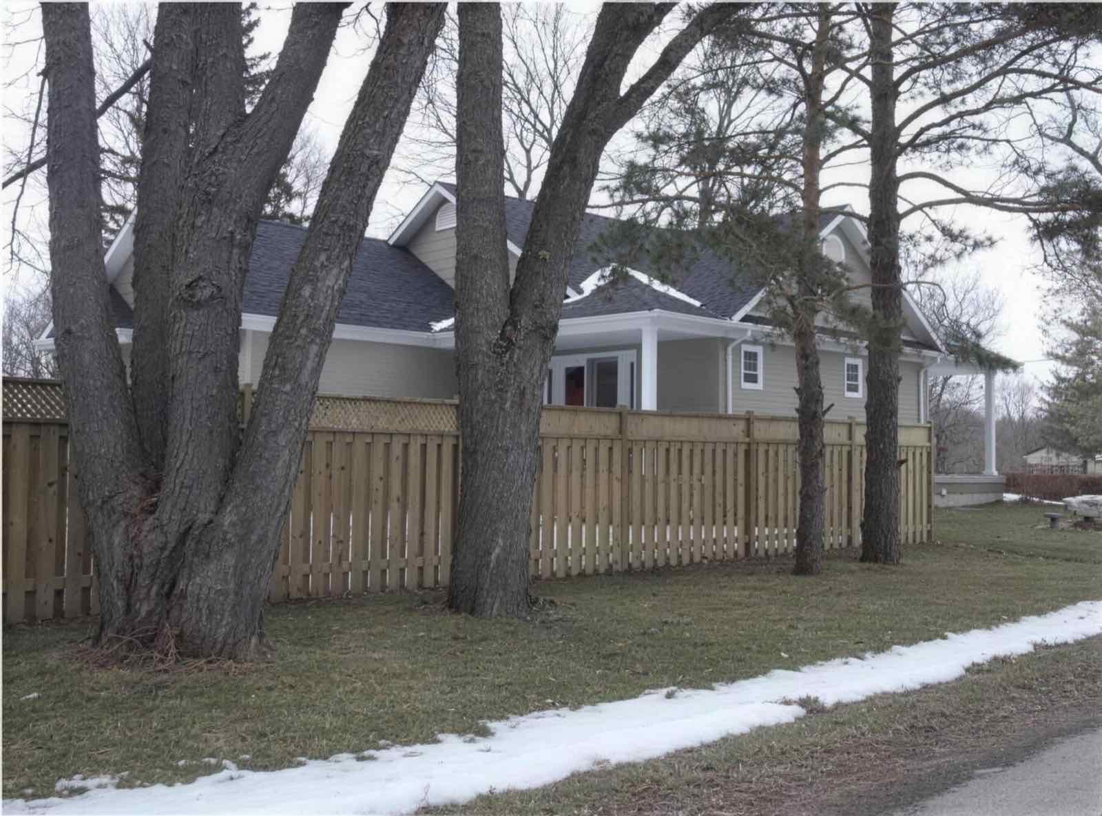 Wood picket fence protecting a front yard through winter snow