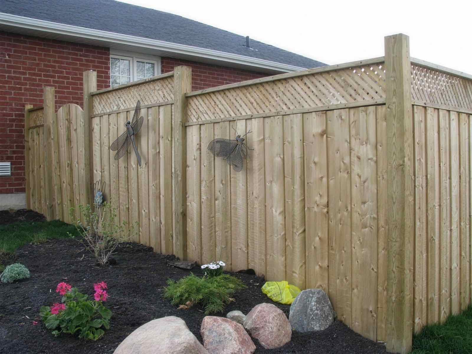Pressure-treated wood privacy fence with a lattice top and arched gate in Peterborough